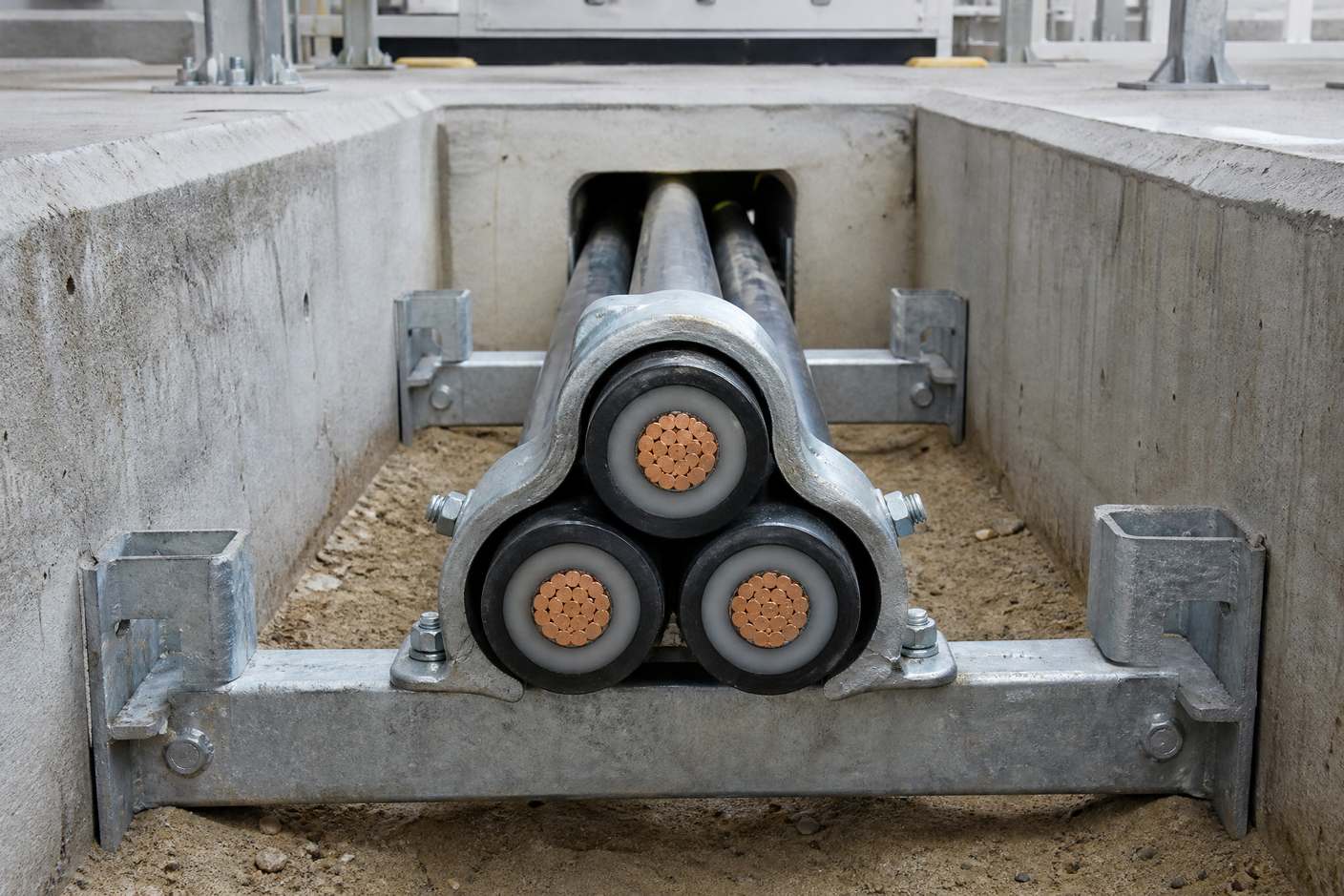 Three single-core cables clamped in trefoil formation, showing the triangular grouping on a substation cable ladder
